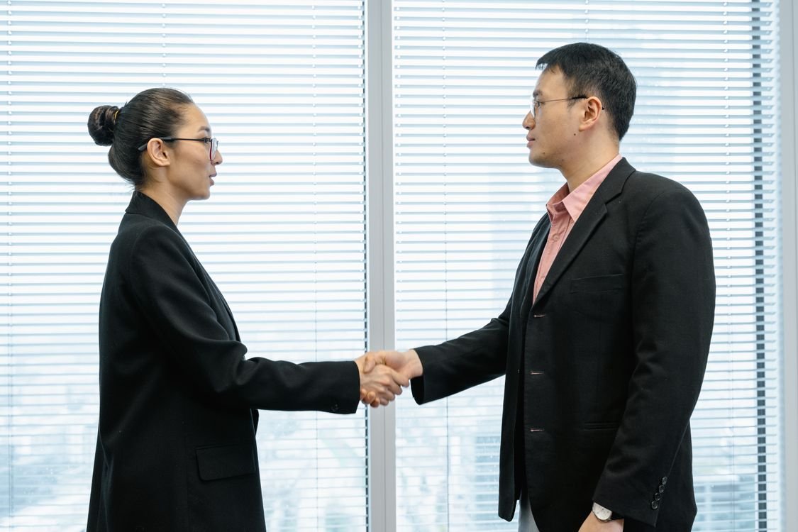 Two business professionals shaking hands in a modern office after successful salary negotiation in Pakistan