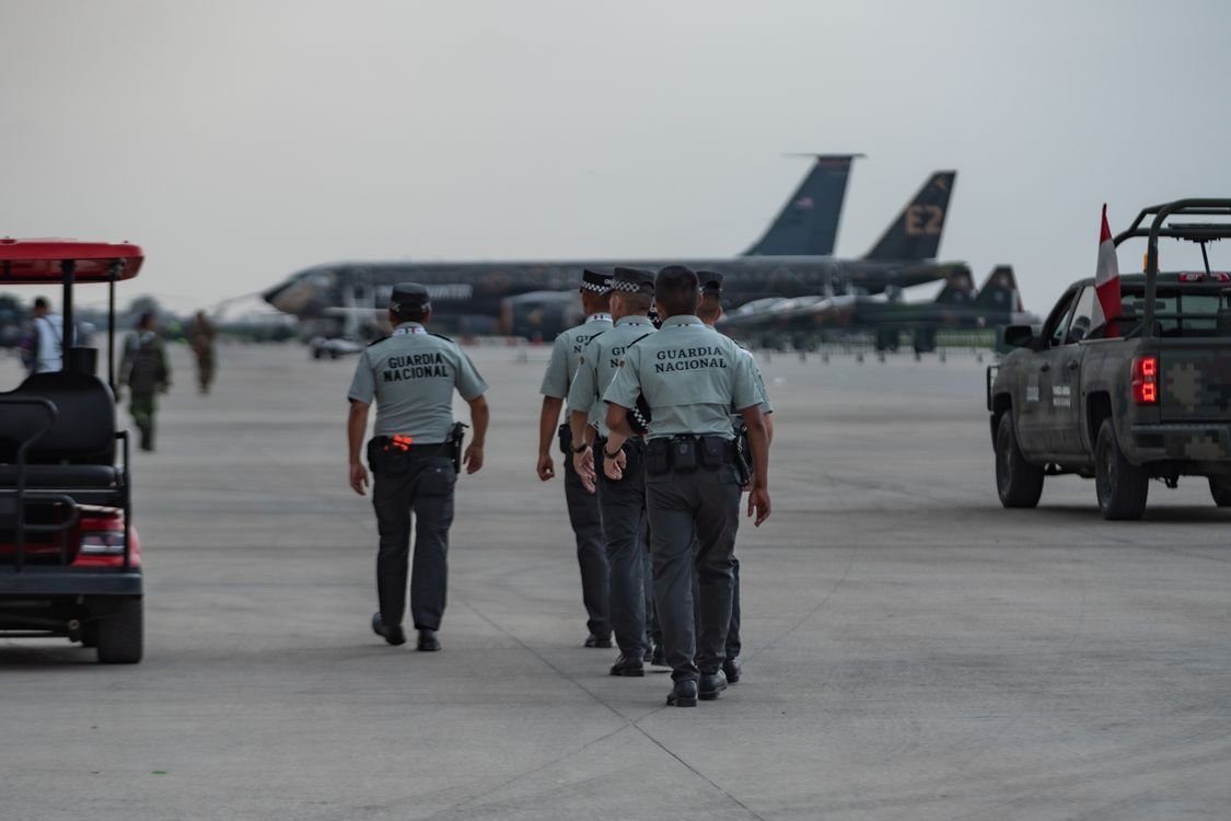 Uniformed airport security officers patrolling an airport tarmac with planes in the background