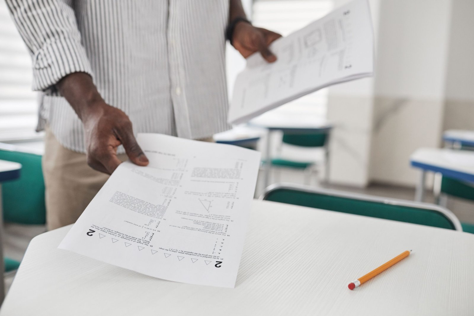 Person arranging examination papers on a desk