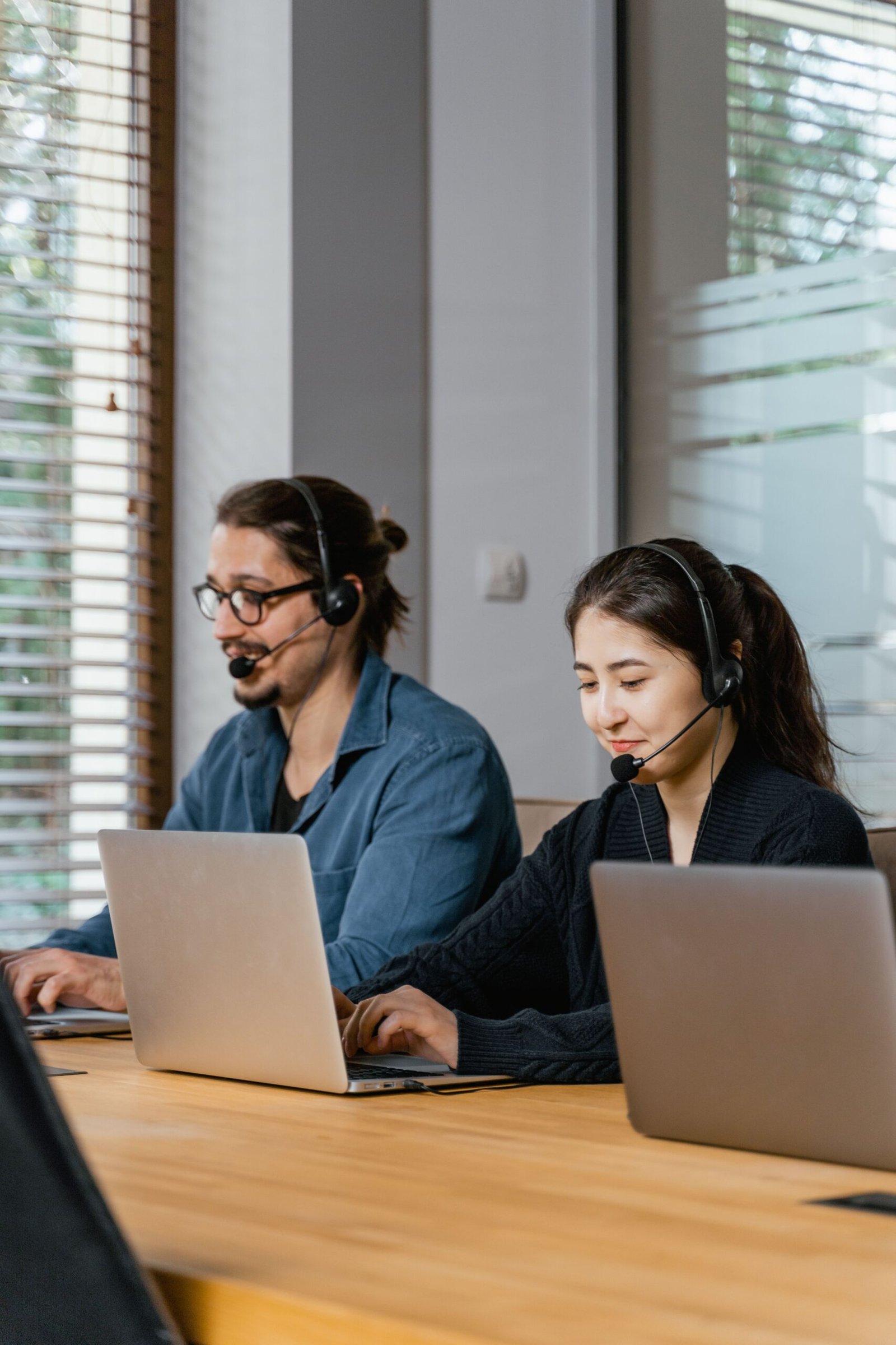 Two call center agents wearing headsets working at computers in a modern BPO office, illustrating call center jobs in Pakistan